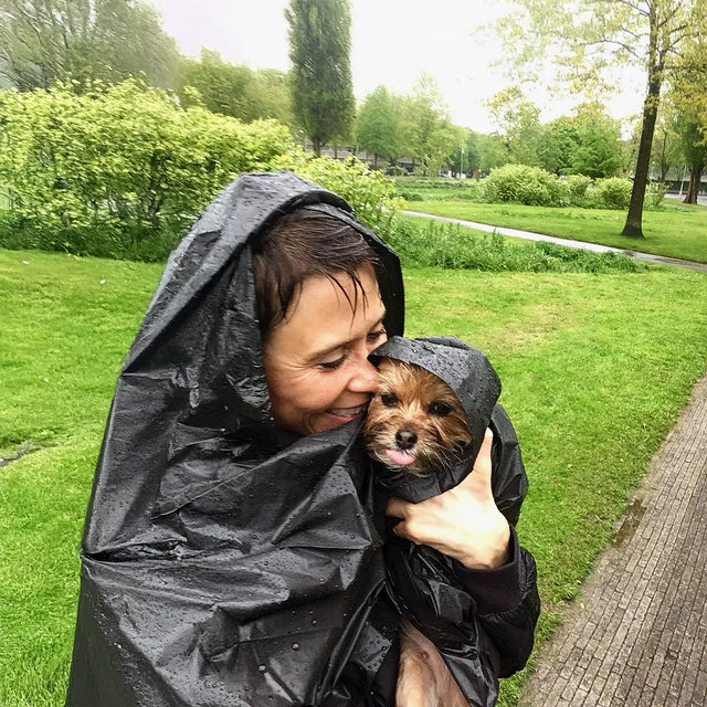 Dog owner and her dog shielded by a black plastic bag, in a park in Amsterdam