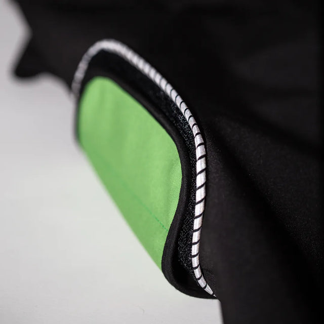 Closeup of a green belly wrap attached to a side loop patch on the modular dog raincoat body, outlined with reflective piping