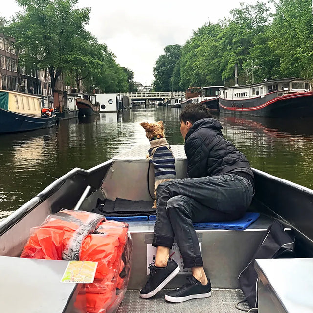 Boat ride in Amsterdam with a dog mom and her dog, framed by canals, boats, and trees