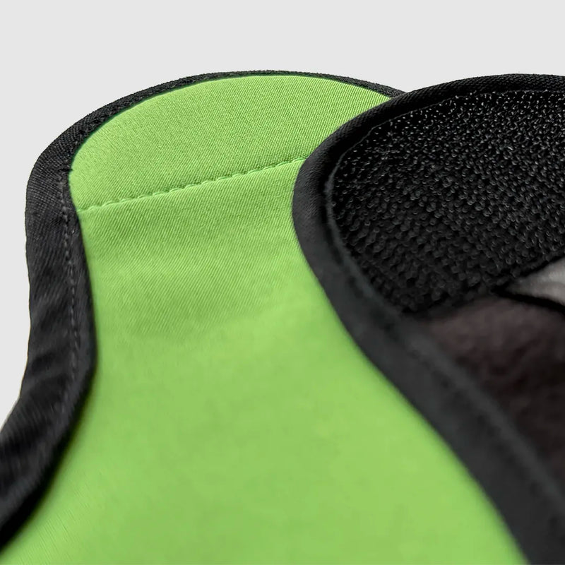 Close-up of a belly wrap, green fabric with black trim on a gray background